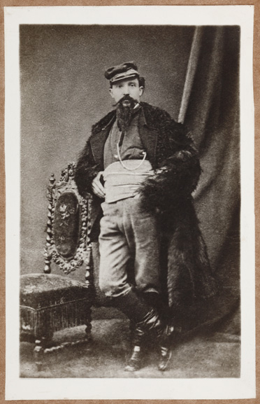 Faustino Tanara. Figura intera, ritratto in piedi, appoggiato allo schienale di una sedia. Sullo sfondo un drappo.
