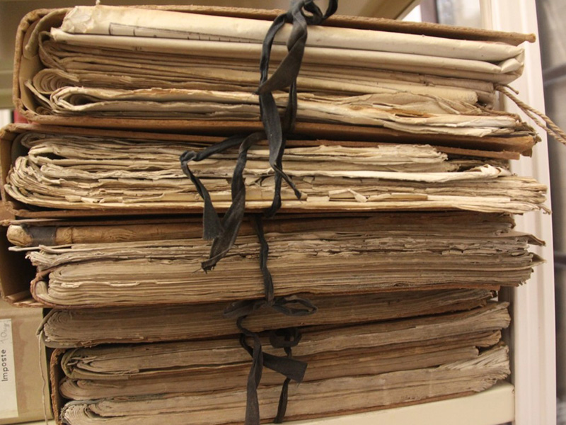 Immagine di pila di documenti legati fra loro, rappresentativa di Archivi Storici